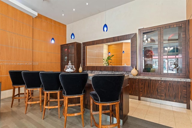 bar featuring hanging light fixtures, a towering ceiling, and light tile patterned flooring