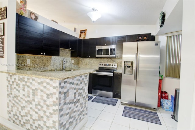 kitchen with sink, stainless steel appliances, kitchen peninsula, vaulted ceiling, and light tile patterned floors