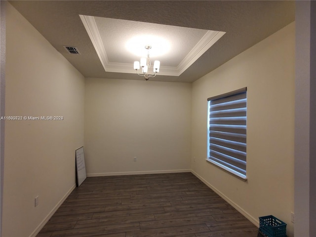 empty room with dark wood-type flooring, an inviting chandelier, a raised ceiling, crown molding, and a textured ceiling