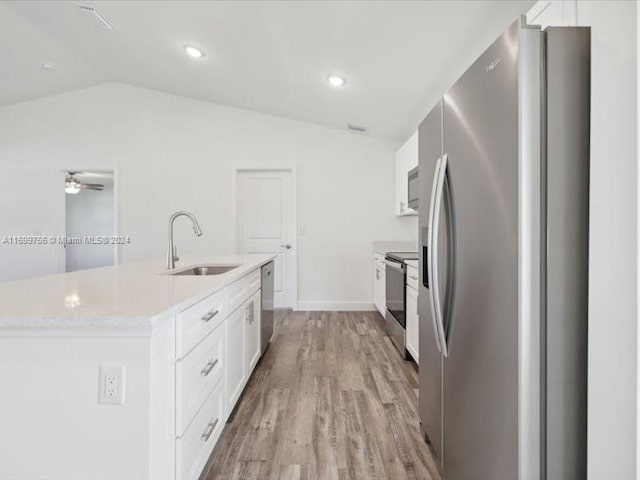 kitchen featuring appliances with stainless steel finishes, vaulted ceiling, light hardwood / wood-style floors, and white cabinetry