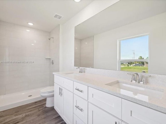 bathroom featuring tiled shower, vanity, hardwood / wood-style flooring, and toilet