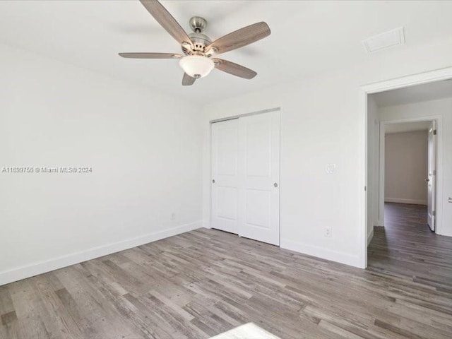 unfurnished bedroom with hardwood / wood-style floors, a closet, and ceiling fan