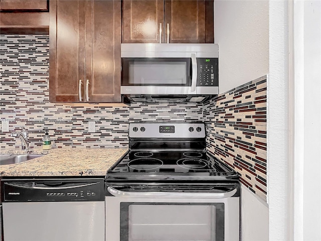 kitchen with backsplash, sink, light stone countertops, dark brown cabinetry, and stainless steel appliances