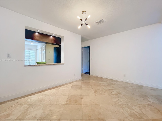 spare room with a textured ceiling and a notable chandelier