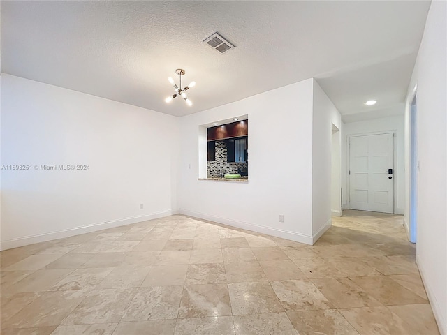 spare room with a chandelier and a textured ceiling