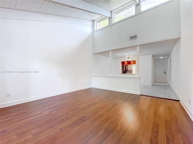 unfurnished living room featuring beamed ceiling, wooden ceiling, and hardwood / wood-style flooring