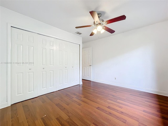 unfurnished bedroom with dark hardwood / wood-style floors, ceiling fan, and a closet