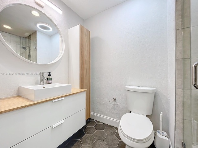 bathroom with tile patterned floors, a shower with door, vanity, and toilet