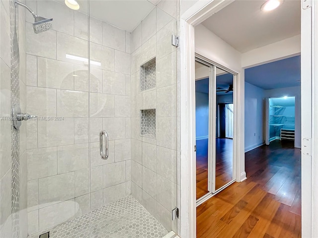 bathroom with wood-type flooring and a shower with shower door