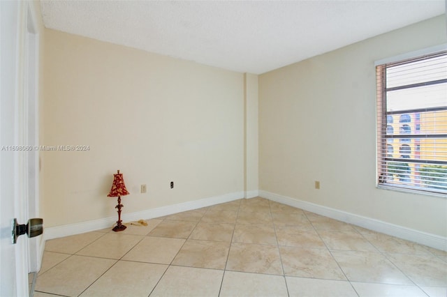 tiled spare room with a textured ceiling and a healthy amount of sunlight