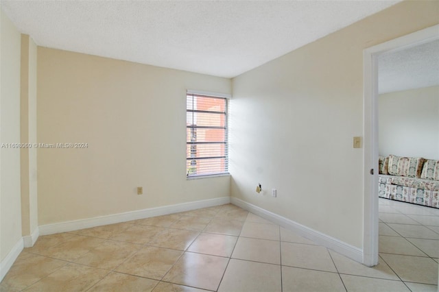 empty room featuring light tile patterned floors and a textured ceiling