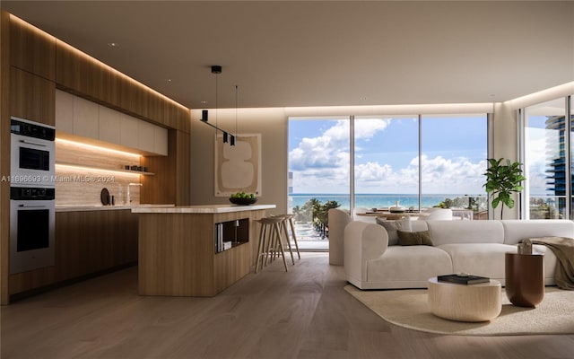 kitchen featuring decorative light fixtures, stainless steel double oven, a water view, and light hardwood / wood-style flooring