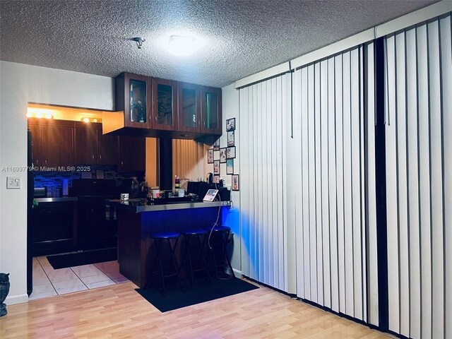 kitchen featuring backsplash, ventilation hood, light wood-type flooring, and a textured ceiling