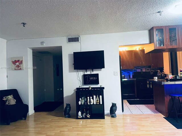 kitchen featuring black appliances, decorative backsplash, light tile patterned flooring, and a textured ceiling