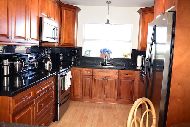 kitchen featuring pendant lighting, sink, decorative backsplash, appliances with stainless steel finishes, and light hardwood / wood-style floors