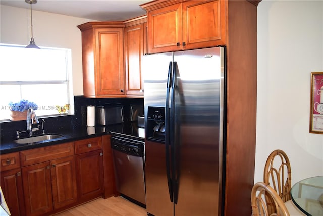 kitchen featuring dark stone counters, sink, light hardwood / wood-style flooring, and appliances with stainless steel finishes