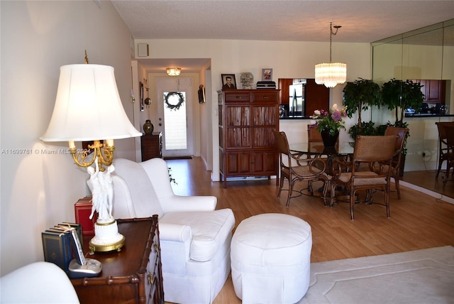 living room with hardwood / wood-style floors, a textured ceiling, and an inviting chandelier