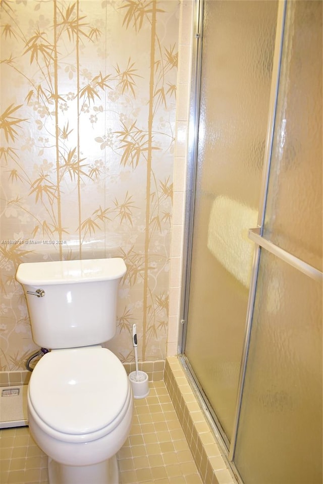 bathroom with tile patterned floors, toilet, and an enclosed shower