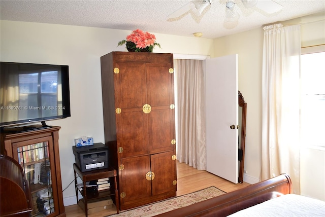 bedroom featuring ceiling fan, a textured ceiling, and light hardwood / wood-style flooring