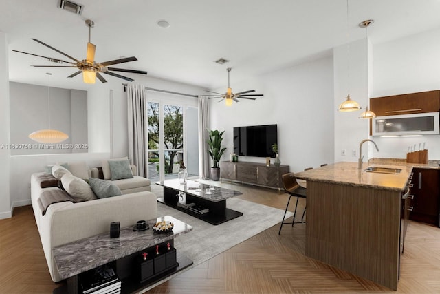 living room featuring light parquet flooring, sink, and ceiling fan