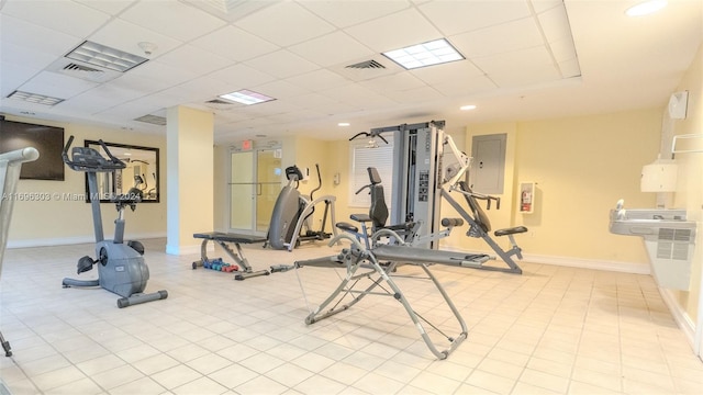 gym with light tile patterned floors and a paneled ceiling