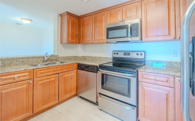 kitchen featuring light stone countertops, stainless steel appliances, and sink