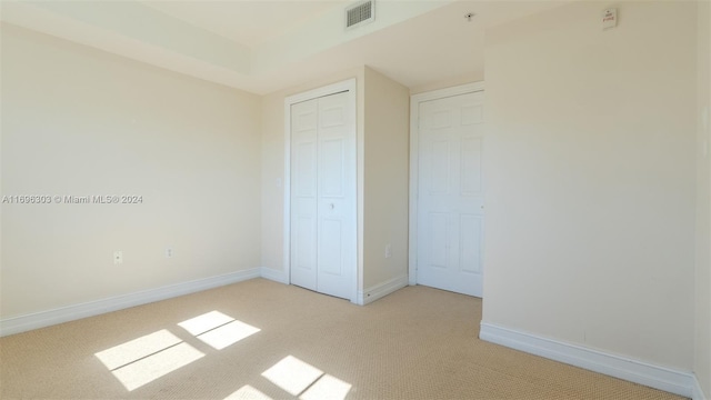 unfurnished bedroom featuring light carpet and a closet