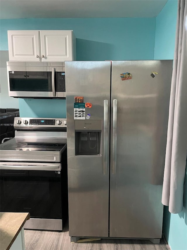 kitchen featuring stainless steel appliances, white cabinetry, and light hardwood / wood-style flooring