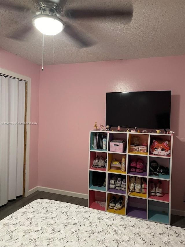 bedroom with ceiling fan, dark hardwood / wood-style flooring, and a textured ceiling