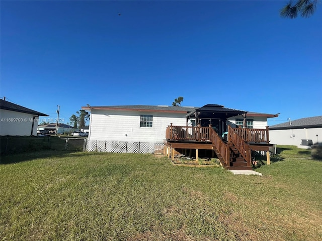 rear view of property with a gazebo, a wooden deck, and a lawn