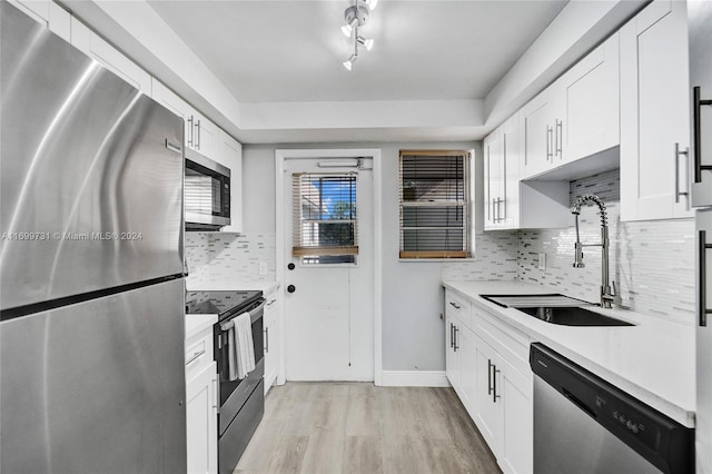 kitchen with light wood-type flooring, white cabinetry, backsplash, and appliances with stainless steel finishes