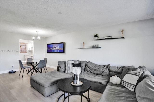 living room featuring light hardwood / wood-style flooring, a textured ceiling, and an inviting chandelier