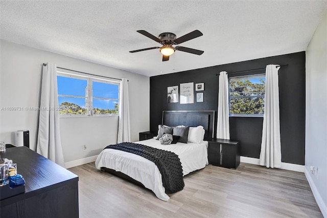 bedroom with multiple windows, ceiling fan, light hardwood / wood-style floors, and a textured ceiling