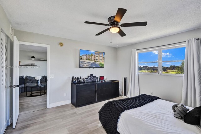 bedroom with ceiling fan, light wood-type flooring, a textured ceiling, and a closet