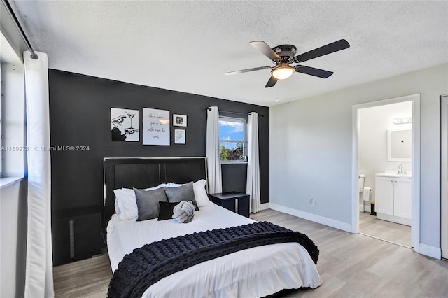 bedroom with ceiling fan, ensuite bathroom, light hardwood / wood-style floors, and a textured ceiling