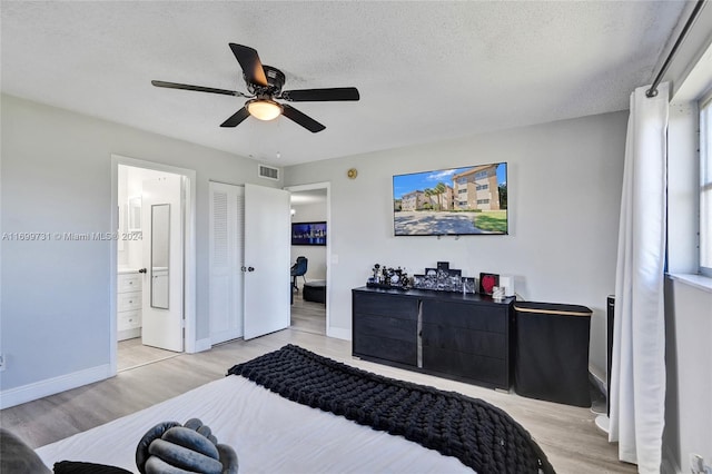 bedroom with connected bathroom, ceiling fan, light hardwood / wood-style floors, a textured ceiling, and multiple windows