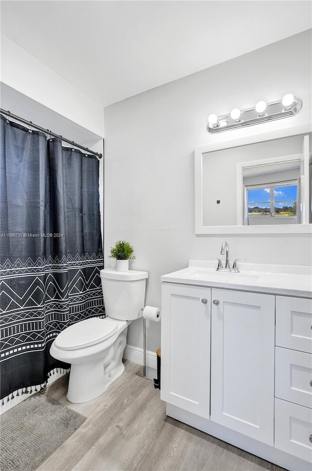 bathroom with curtained shower, vanity, wood-type flooring, and toilet