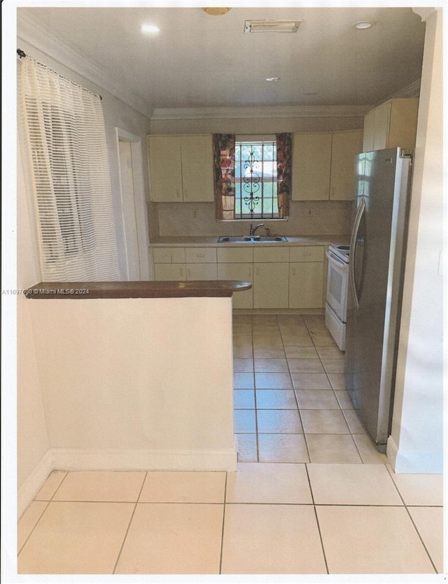 kitchen with white stove, crown molding, sink, stainless steel fridge, and light tile patterned floors