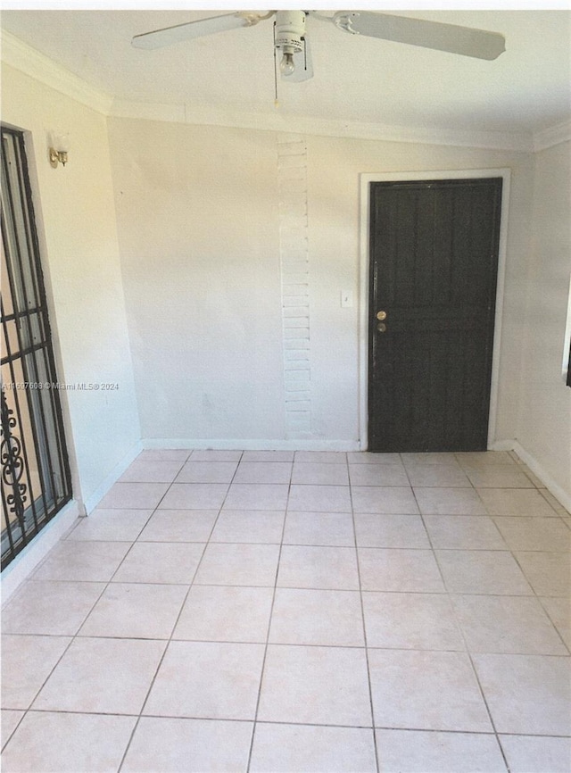 spare room with ceiling fan, light tile patterned floors, and crown molding