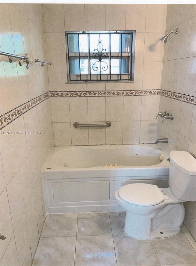 bathroom with toilet, tile patterned flooring, tile walls, and tub / shower combination