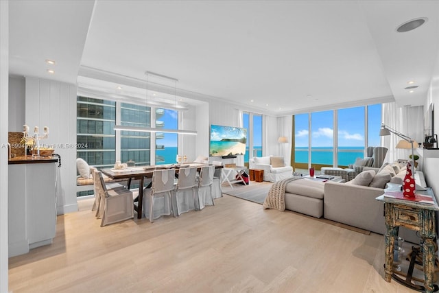 living room with light hardwood / wood-style floors, a water view, and a wall of windows