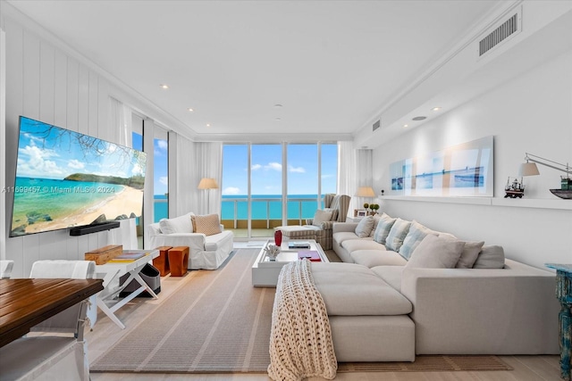 living room featuring expansive windows, a wealth of natural light, a water view, and light hardwood / wood-style floors