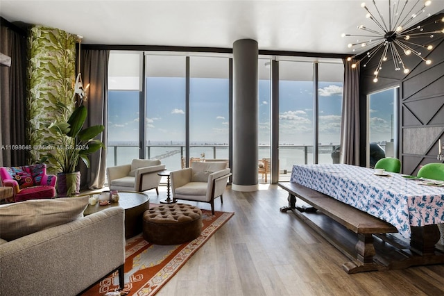 bedroom featuring access to exterior, an inviting chandelier, a wall of windows, a water view, and hardwood / wood-style flooring