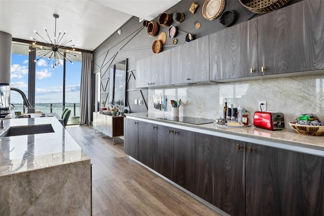 kitchen featuring sink, hanging light fixtures, backsplash, floor to ceiling windows, and light wood-type flooring