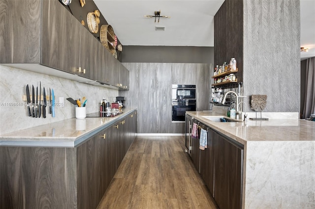 kitchen featuring dark brown cabinets, sink, light wood-type flooring, and black appliances