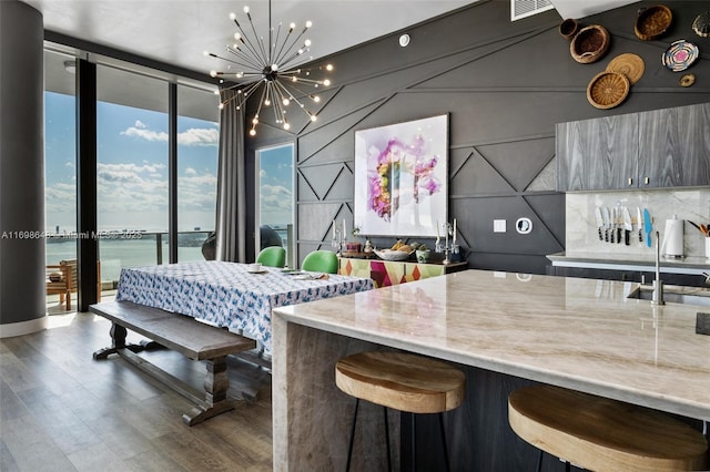 interior space with floor to ceiling windows, a water view, wood-type flooring, light stone countertops, and a chandelier