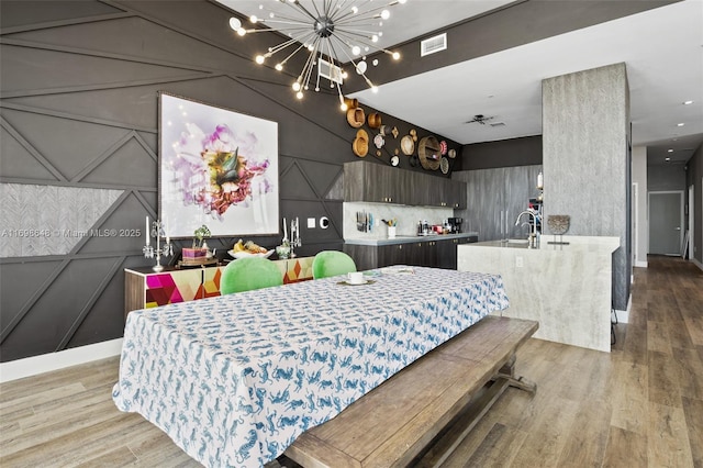 dining room with a notable chandelier, light hardwood / wood-style floors, and sink