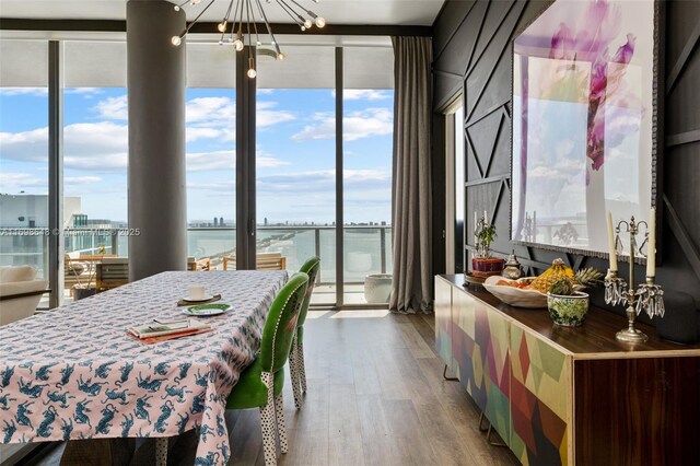 bedroom featuring a water view, a wall of windows, an inviting chandelier, and light wood-type flooring