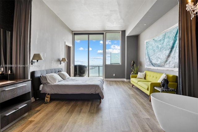 bedroom with access to exterior, light hardwood / wood-style flooring, and floor to ceiling windows