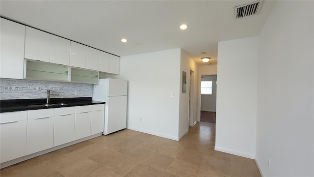 kitchen with sink, electric panel, white fridge, decorative backsplash, and white cabinets